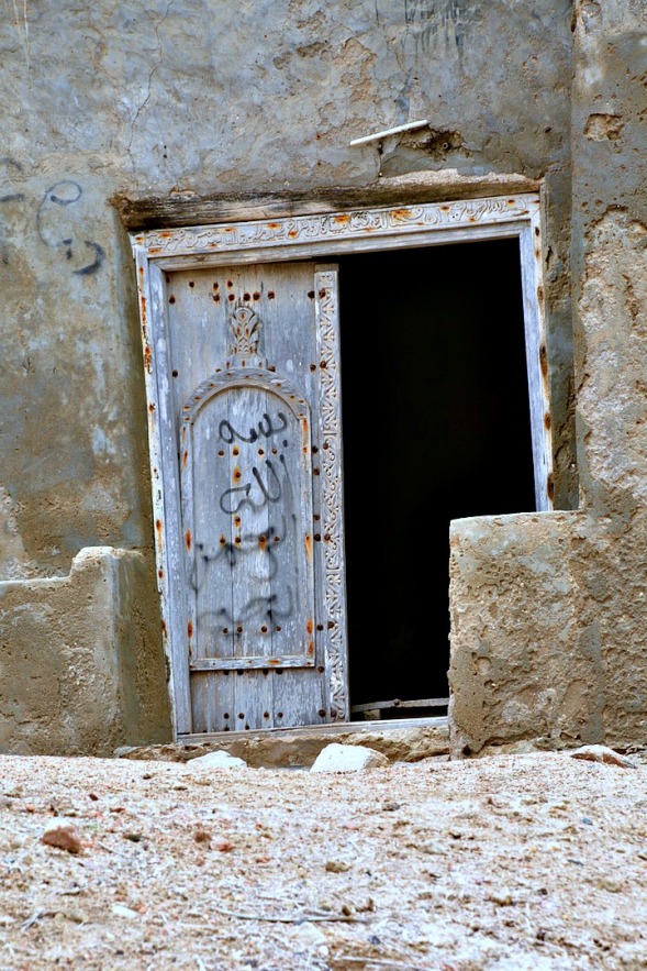 A crooked door with Arabic inscription carved into the lintel...